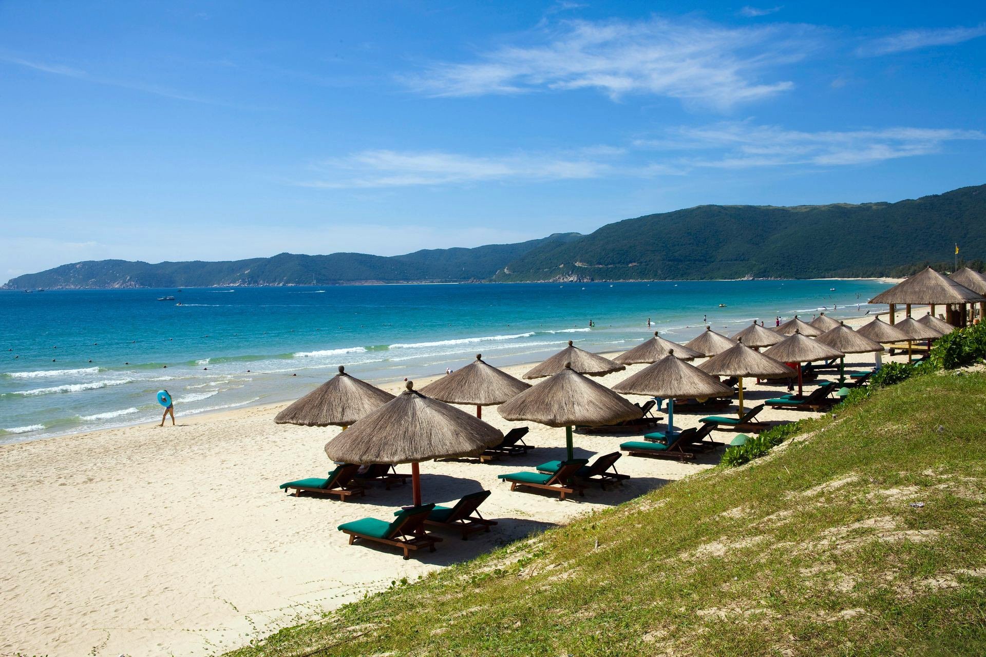 meer ozean küste strand sand sonnenschirme stroh ferne himmel berge resort erholung liegestühle brandung