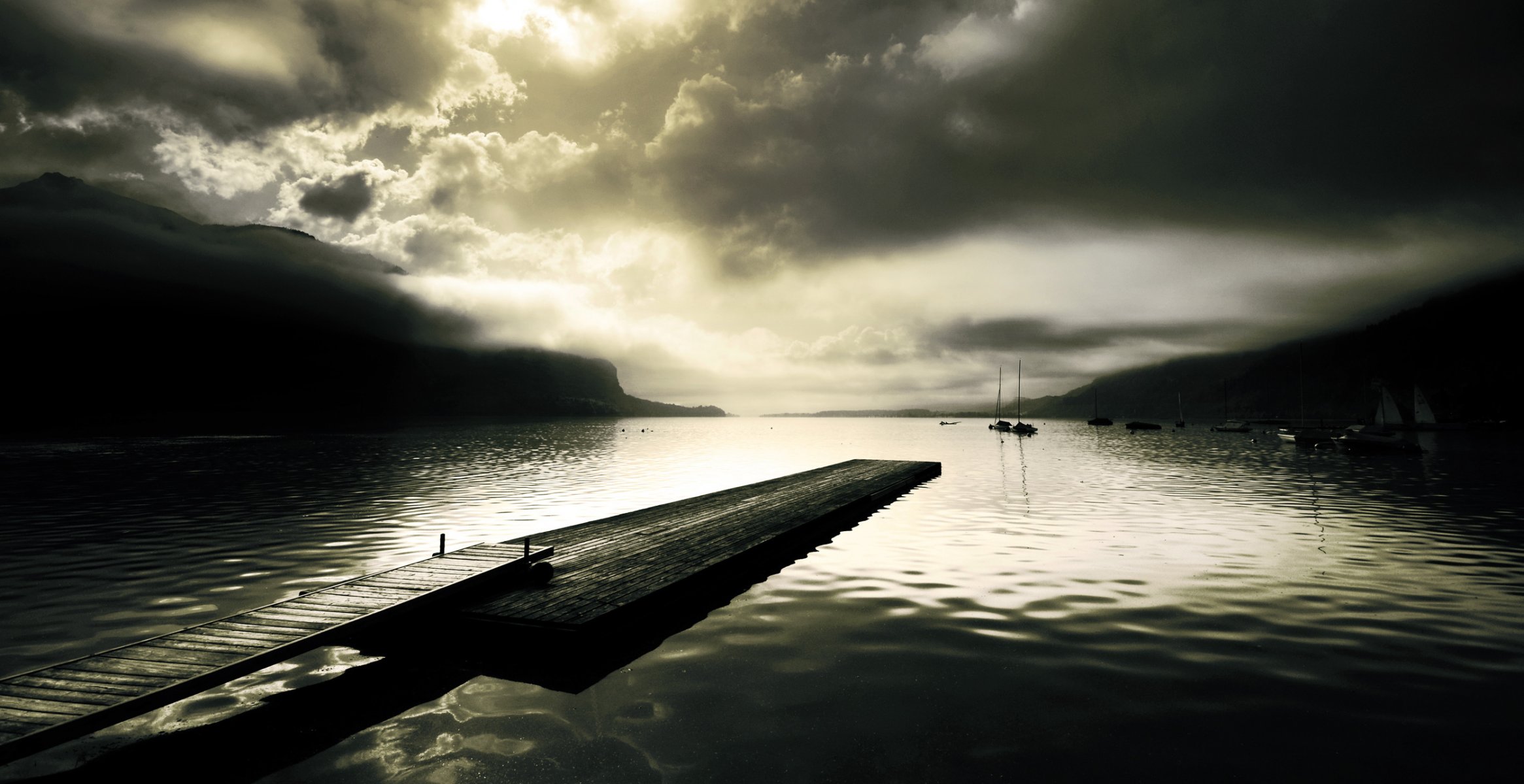 lake surface pier pier pier planks hills ships sailboat yachts fog