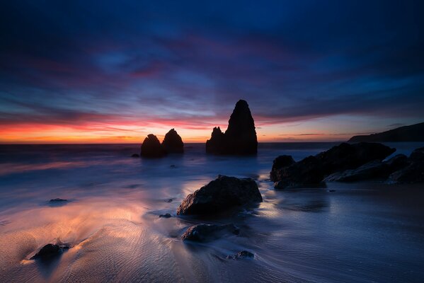 The shore of the bay with picturesque stones on the background of sunset