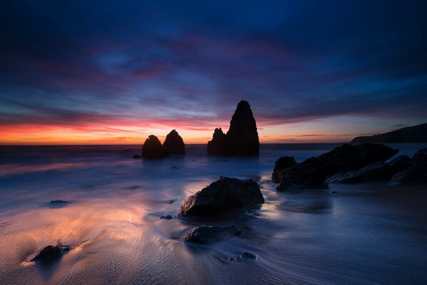 Costa de la bahía con piedras pintorescas en el fondo de la puesta de sol