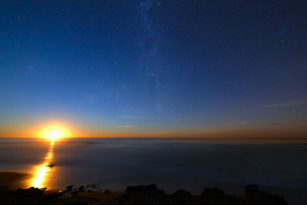 Sunrise in the starry sky over the ocean