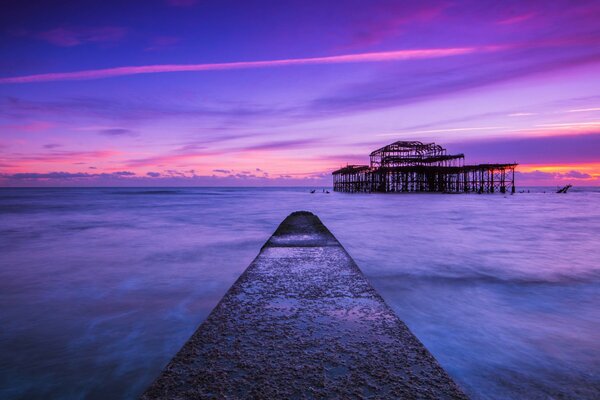 Muelle que se adentra en el mar lila al atardecer