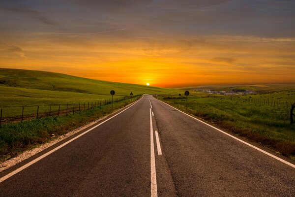 Asphaltierte Straße, die in den Sonnenuntergang führt