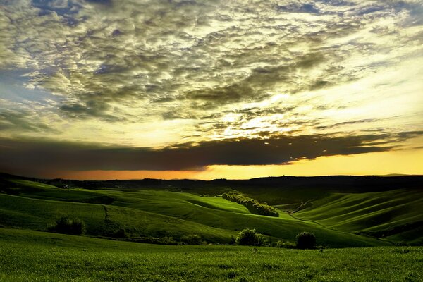 Green hills in the light of an orange sunset