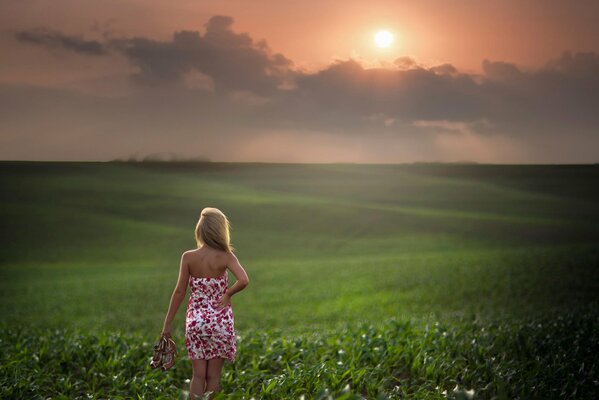 A girl walks through a green field