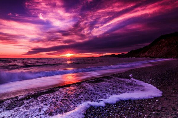 Lilac sunset and foam wave on the beach