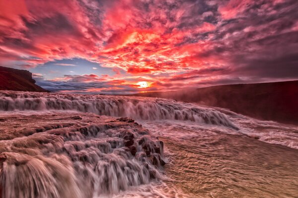 Scharlachroter Sonnenuntergang über dem Wasserfall