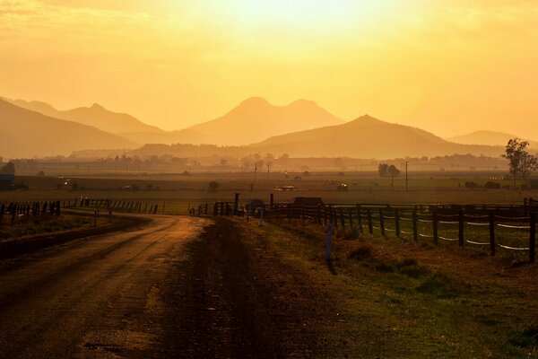 Ein Weg mit schöner Landschaft führt über einen Zaun