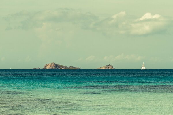 Velero blanco en el océano frente a las islas