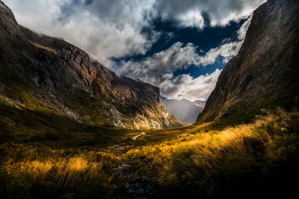 The road between the mountains with clouds and the sun