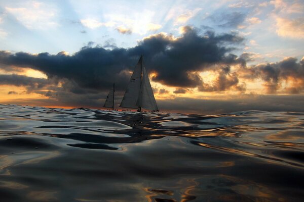 La mer au coucher du soleil et les voiliers au loin