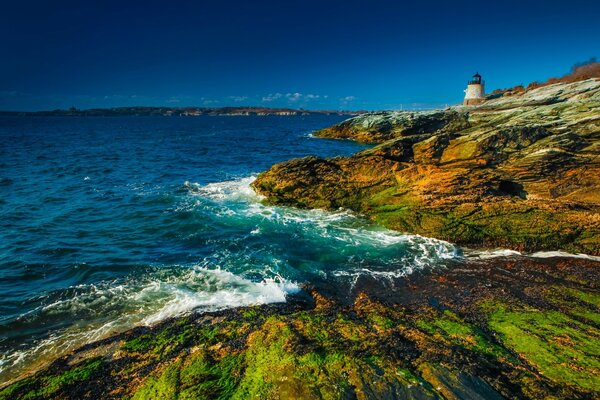 Lighthouse on a rocky shore. The sea is stormy