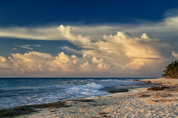 Das berauschende Meer am Sandstrand und die dichten Wolken am Himmel