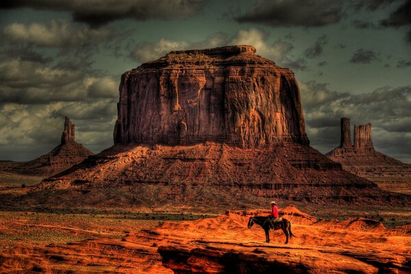 Cow-Boy à cheval pendant le coucher du soleil dans le désert
