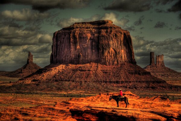 Cowboy a cavallo durante il tramonto nel deserto