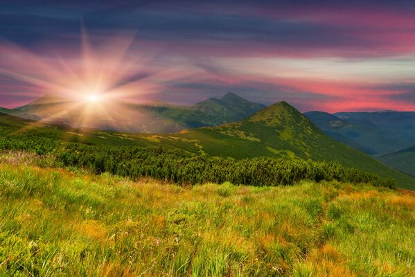 Soleil radieux au coucher du soleil sur le fond de la pente des montagnes