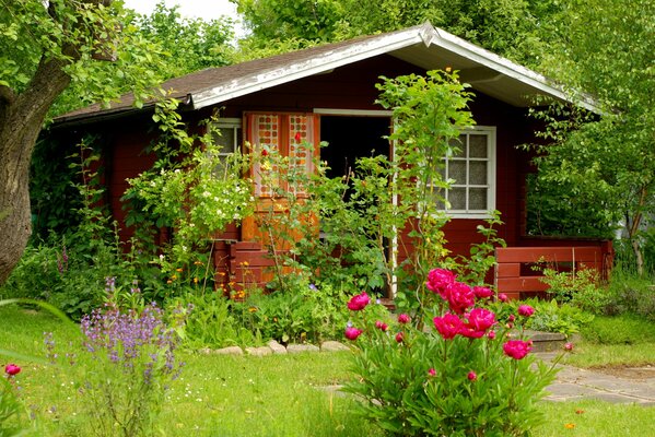 Sommerhaus vor dem Hintergrund von Blumen und grünen Bäumen