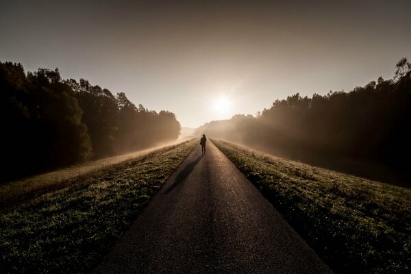 Obraz człowiek rano na drodze we mgle