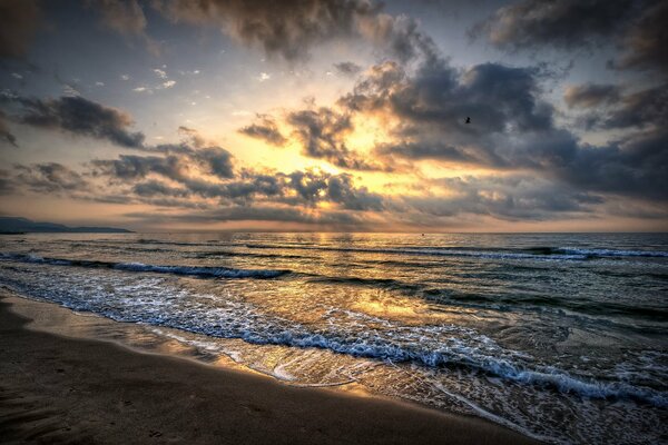 Mare con onde e sabbia durante il tramonto