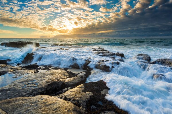 Die Sonne, die sich durch die Wolken am Meer schlägt