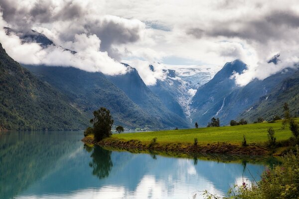 Clouds in the mountains over a green meadow in Norway