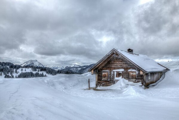 Casa de madera en las montañas cubiertas de nieve