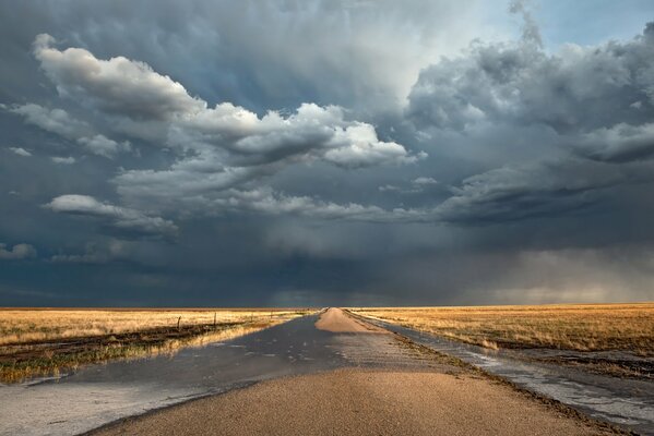 Eine Straße mit einem endlosen Feld und bewölktem Wetter