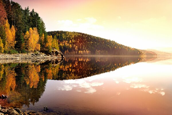 Herbstliche Abendlandschaft mit Bergen, Sonnenuntergang, Seeufer und gelben Blättern