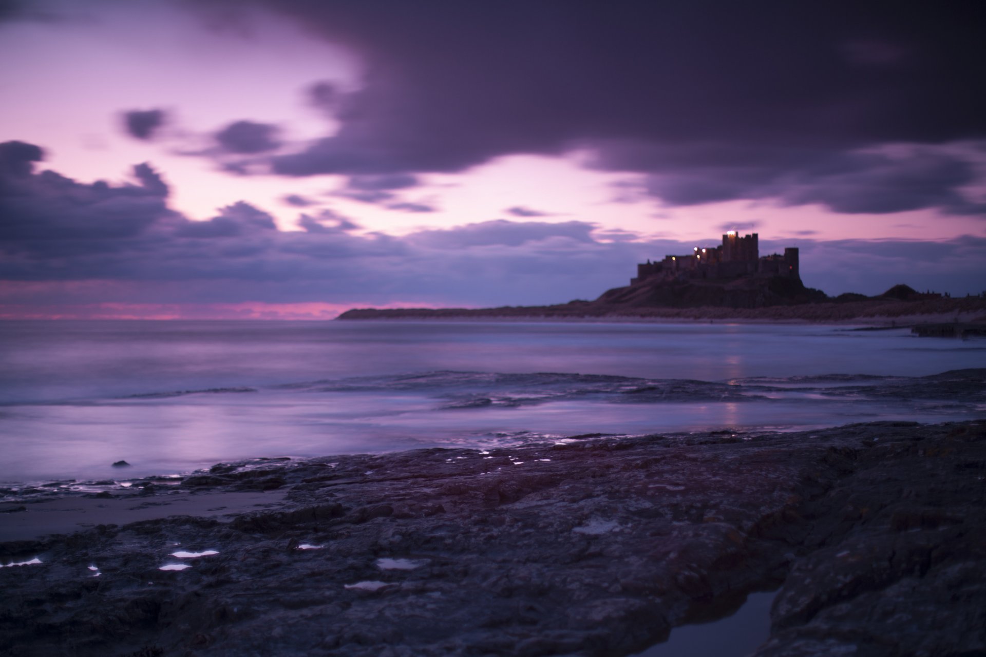 wielka brytania anglia bamburgh castle morze wybrzeże wieczór fioletowy niebo chmury zamek brzeg liliowy fioletowy chmury krajobraz