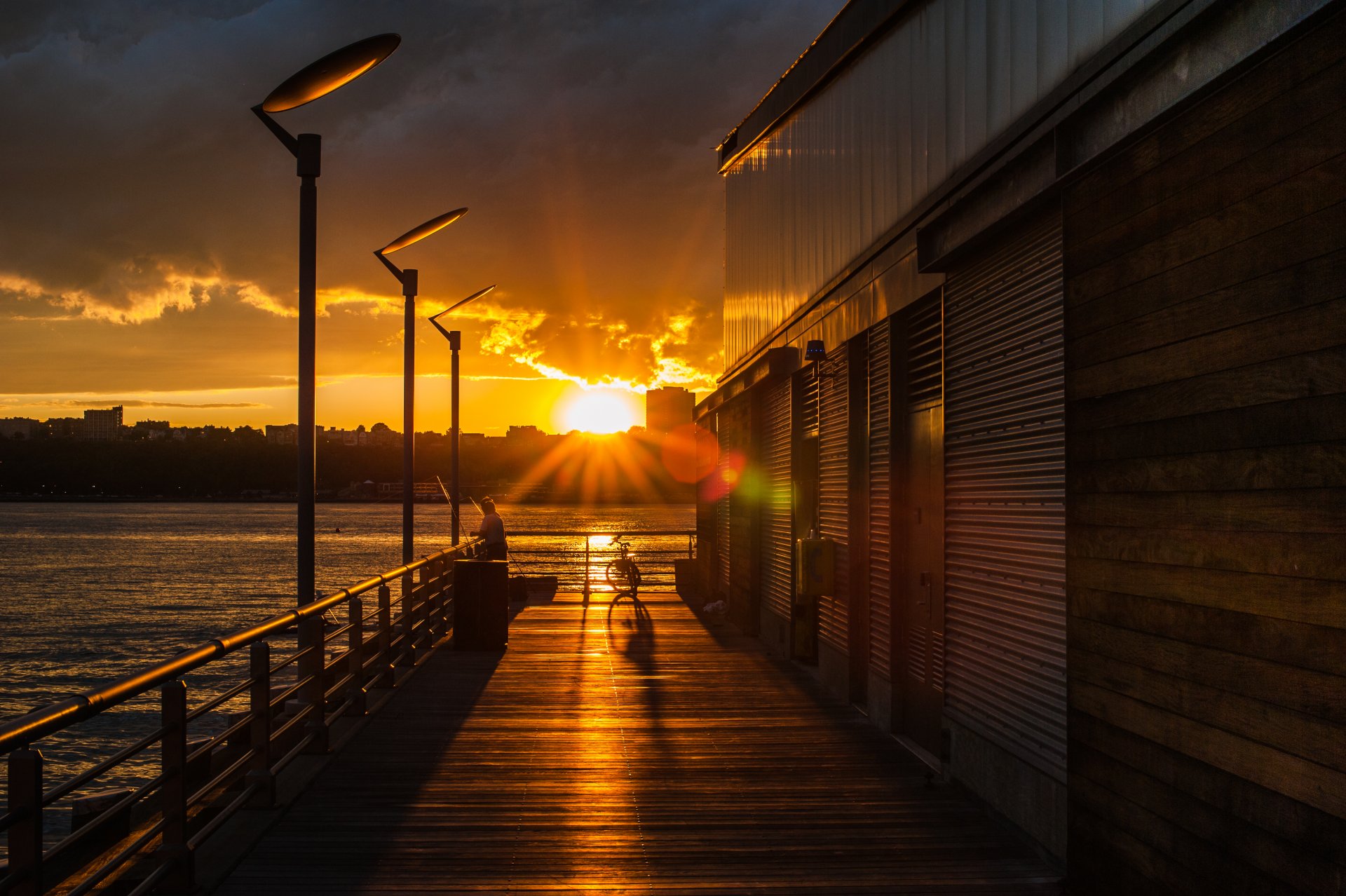 city evening sunset sun sky clouds trees sea lake water lamps bicycle