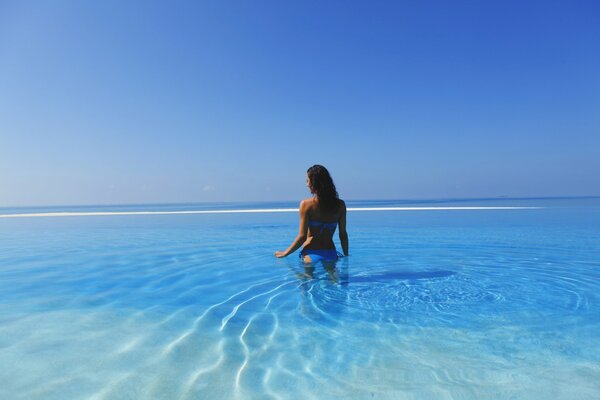 A girl in a blue swimsuit standing in the water