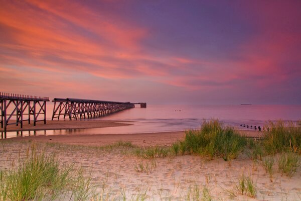 Sonnenuntergang am Meer mit Sand und Pier