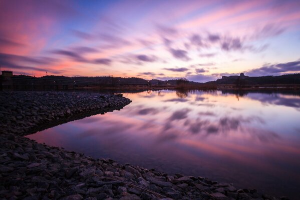 Reflejo de las nubes en el agua entre la orilla rocosa