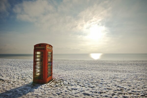 Telefonzelle am Strand im Winter vor Sonnenuntergang Hintergrund