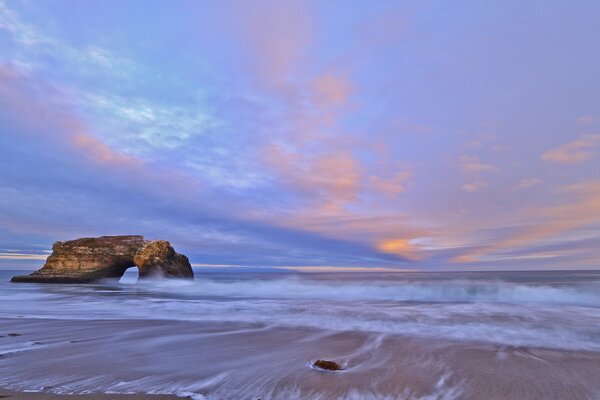 Oleaje de olas azules con espuma de mar blanca, con rocas raras en la costa