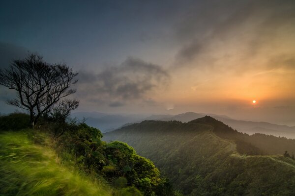 Amanecer en las montañas en la niebla y las nubes