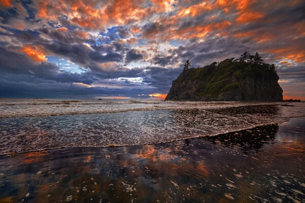 Strand vor dem Hintergrund von Felsen und Sonnenuntergang