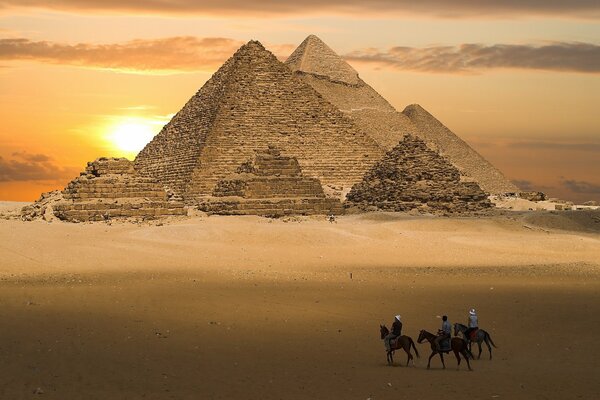 Image d une pyramide jaune vif sur fond de coucher de soleil, cavaliers dans le désert