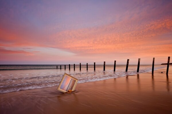 Immagine nella sabbia vicino al mare su uno sfondo di cielo rosa