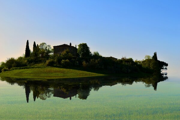 Das Haus auf der grünen Insel spiegelt sich im Wasser wider