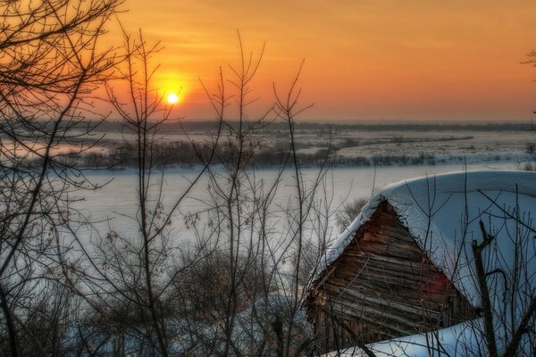 Tramonto sulla foresta invernale e capanna