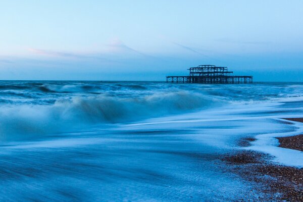 Steinstrand, blauer Himmel und tosende Wellen