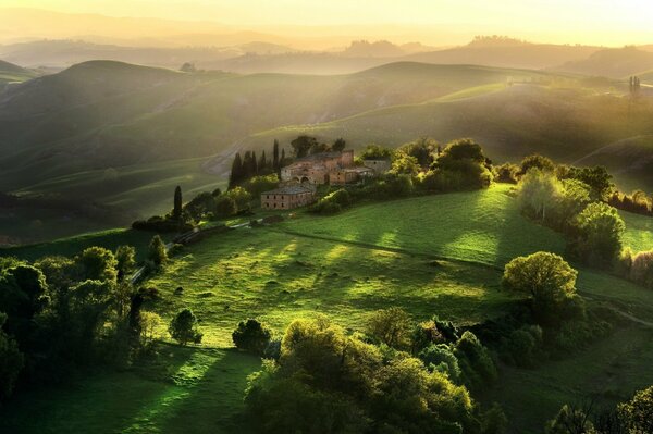 A house on a green hill surrounded by trees