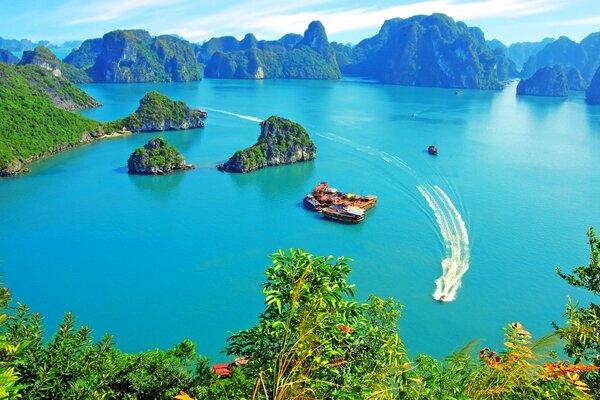 Pleasure boat in Halong Bay with bright vegetation and blue sky