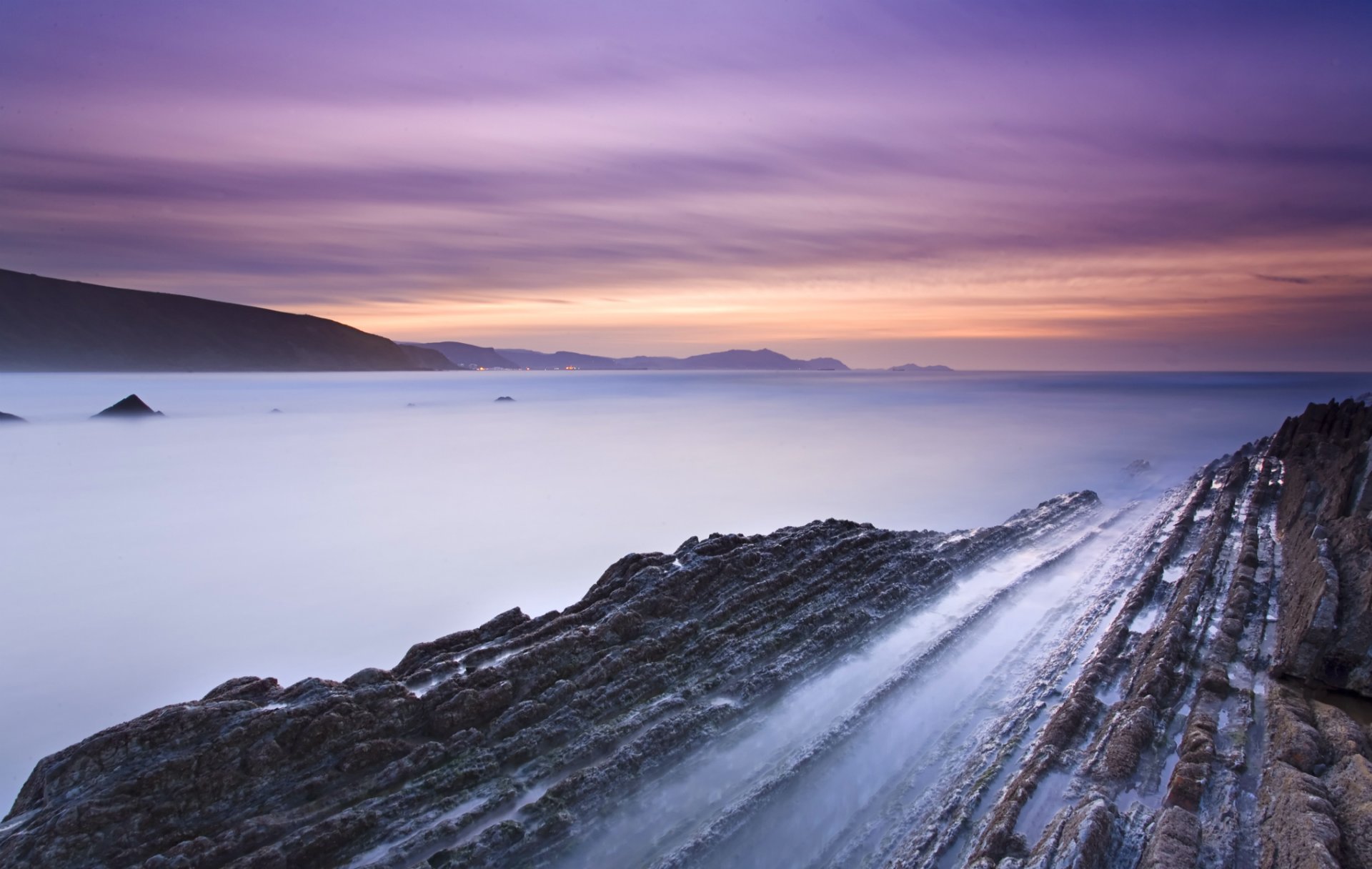 spagna costa rocce baia marea sera tramonto arancione cielo lilla