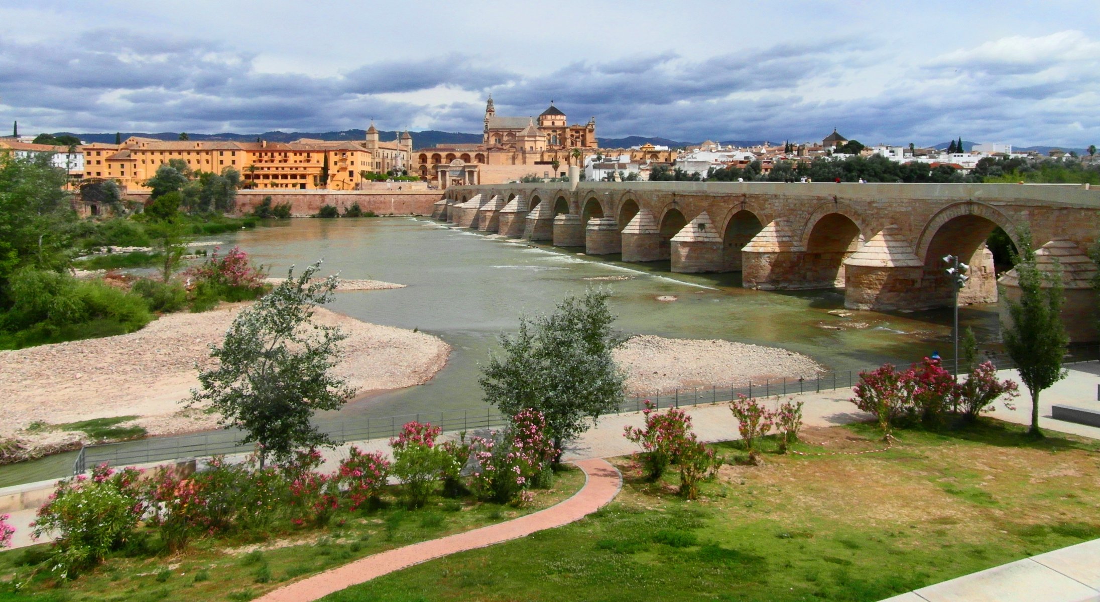 cordoba andalusia spain river guadalquivir 16-frame roman old bridge embankment tree bush flower