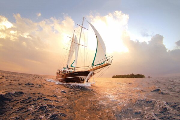 A masted ship on white sails among the waves of the sea