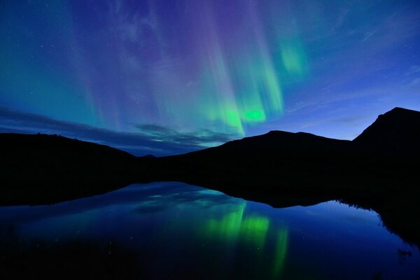 La Aurora boreal en el reflejo de un lago en Noruega