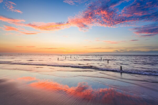 I pilastri sono visibili nella baia e il tramonto si riflette nell acqua