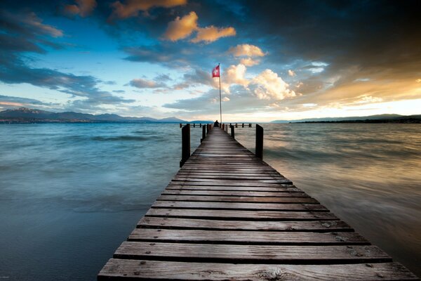 Pier going into the sea, against the background of the evening cloudy sky